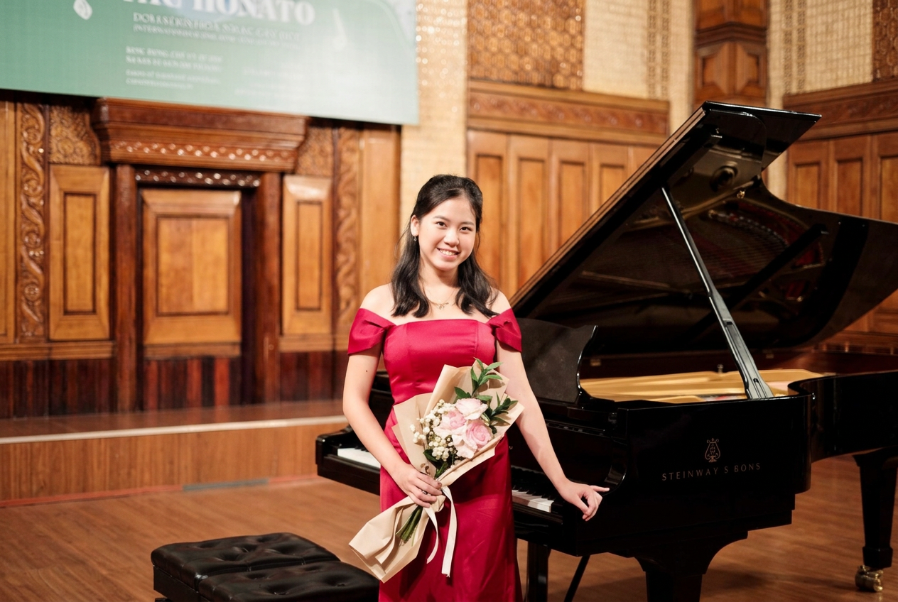 Pianist Chi Vu holding roses beside a Steinway grand piano